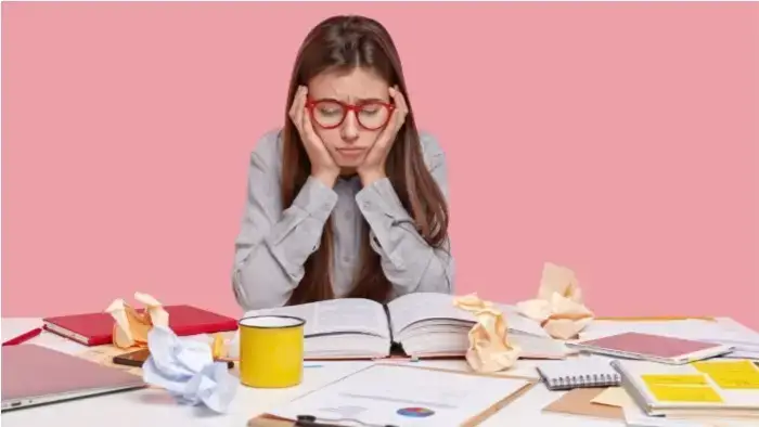 obstáculo aprovação vestibular, mulher estudando com livros e papéis na mesa