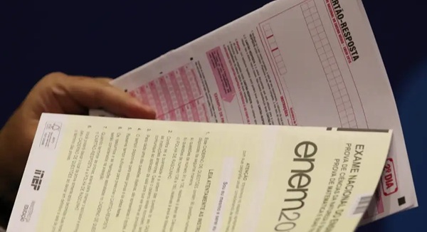 pessoa segurando provas do enem, gabarito resultado enem