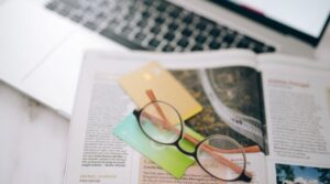 óculos em cima de mesa com notebook e livro, estudar para o enem com ferramentas de ia